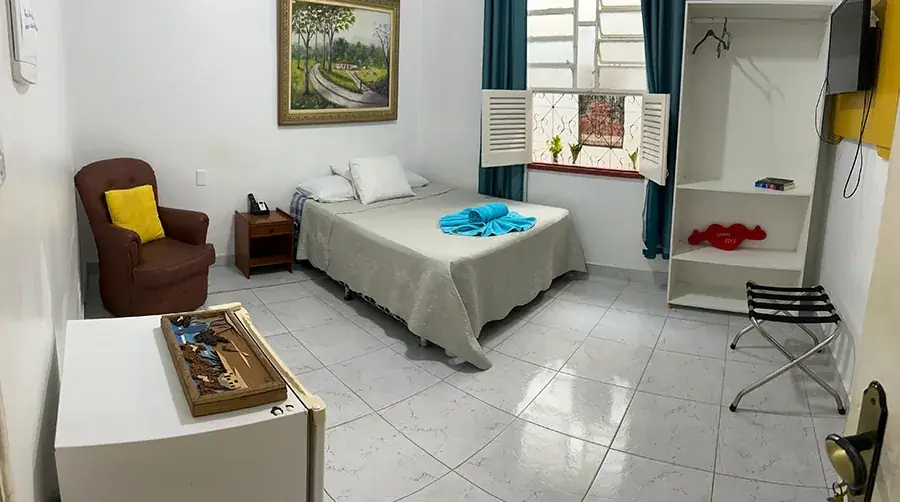 Suíte privativa com cama de casal, ar-condicionado e janela